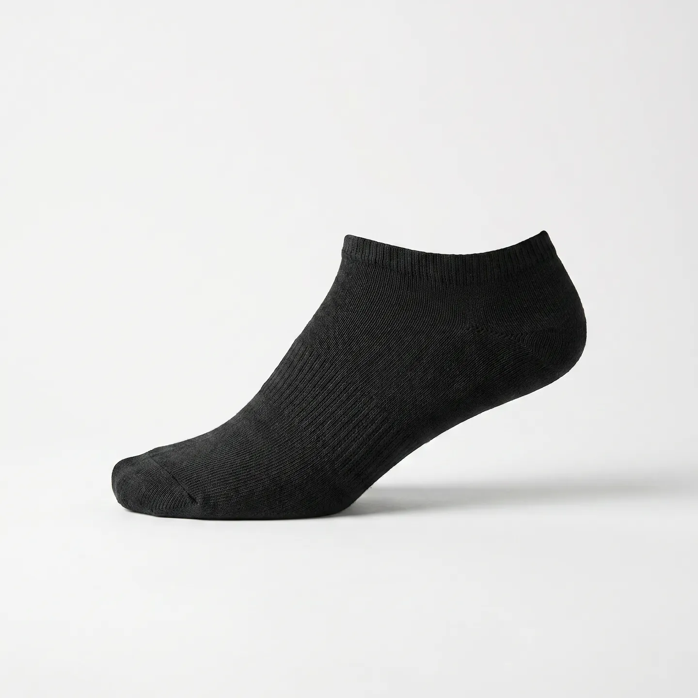 Side profile of a foot wearing a non-toxic low cut sock made with 97 percent cotton that fits invisibly below the shoe line.